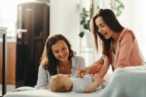 a maternity nurse and mother playing with the baby at home